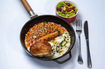 Homemade scrambled eggs with sausages in a pan on a light background. Classic breakfast. View from above. place for writing	
