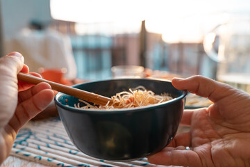closeup of two hands eating japanese food - relaxing on an outdoor balcony at