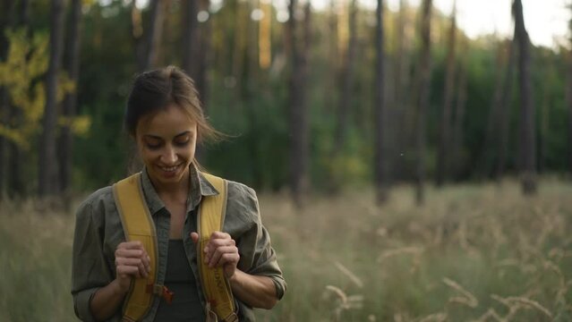 slow motion footage woman with yellow backpack Walks by trail in autumn forest. female hiker with backpack going up through wood with high grass. selective focus. traveling in Ukraine