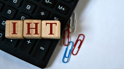 IHT - acronym on wooden cubes against the background of a calculator and paper clips. Copy space