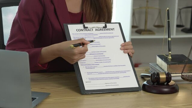 Young Asian female lawyer people reviewing legal documents at desk, embodying reliability, dedication in legal profession, reading announcement. Court convicting defendant according to criminal law