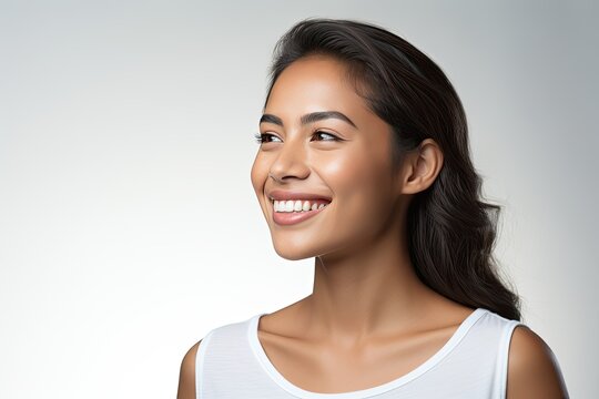 A close-up portrait photograph of a lovely young Asian Indian model woman showcasing a bright smile with clean teeth, perfect for a dental advertisement. 
