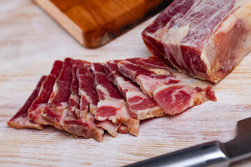 Meat snack, sliced cured pork shoulder on wooden board