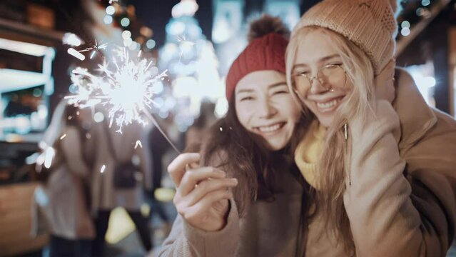 Lesbian lgbt pride friends having fun with sparklers outdoor celebrating merry Christmas xmas and happy new year. Two women portrait smiling waving firework express joy happiness. Christmas holiday