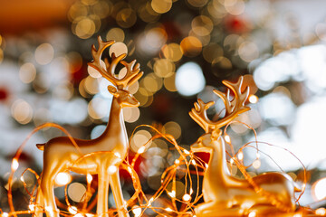 Christmas tree, red balls and shining garland.Christmas wallpaper. Christmas golden deers with...
