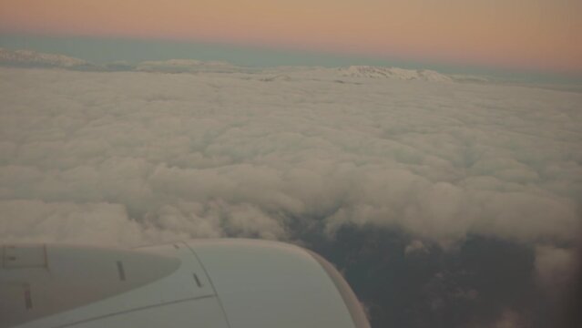 Aircraft flying over clouds and tops of mountain 