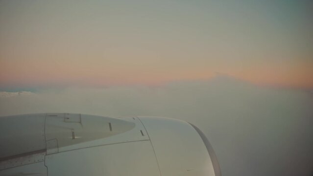 The plane flies through the clouds and fog at dawn