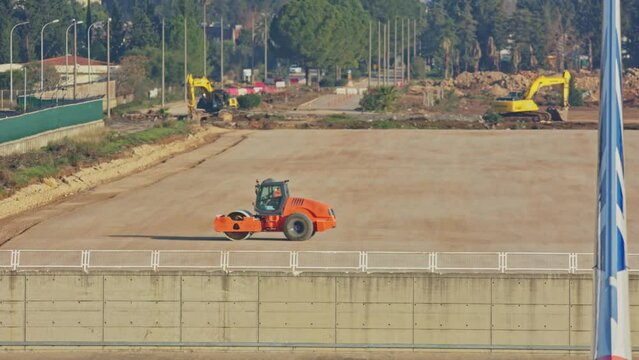 Road roller and excavators on construction site