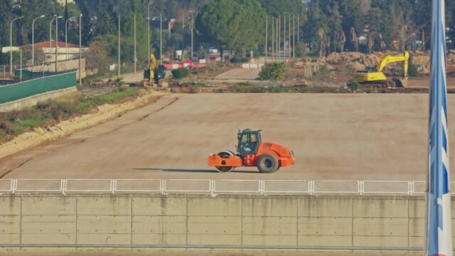 Orange road roller and yellow excavatorson 