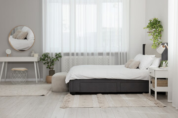 Fototapeta na wymiar Stylish bedroom interior with large comfortable bed and ottoman near window