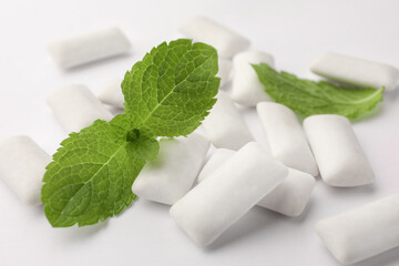 Tasty chewing gums and mint leaves on white background, closeup