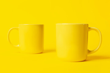 Two bright ceramic mugs on yellow background