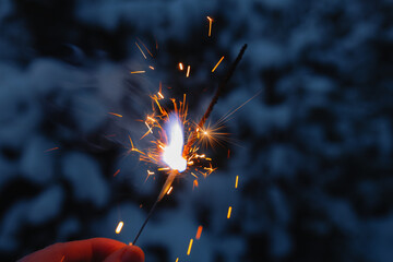 burning sparkler in hand on blue background, concept of holiday