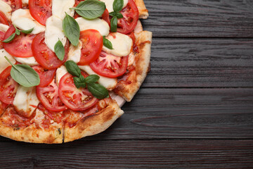 Delicious Caprese pizza with tomatoes, mozzarella and basil on dark wooden table, top view. Space for text