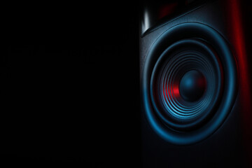 One sound speaker in neon light on black background, closeup. Space for text