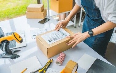 startup young female small business owners attaching shipping labels to cardboard boxes or parcels for delivery of customer orders-concept shopping online