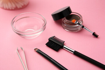 Eyebrow pomade with henna effect and professional tools on pink background