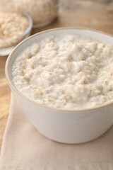 Tasty boiled oatmeal in bowl on table, closeup