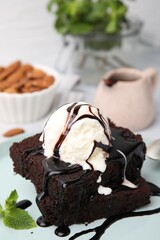 Tasty brownies served with ice cream and chocolate sauce on plate, closeup