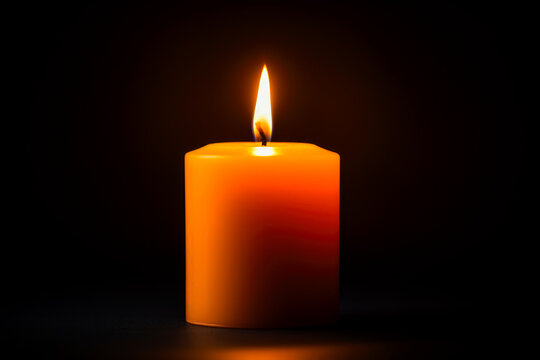 Closeup of a glowing orange candle in the dark, Christmas or warmth concept