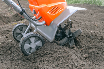 Electric cultivator for cultivating soil in vegetable garden. Side view.