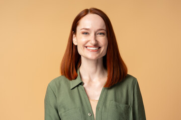 Happy redhead businesswoman smiling on beige background