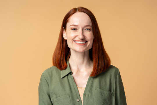 Happy redhead businesswoman smiling on beige background