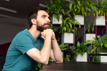 Portrait of handsome bearded hipster man thinking planning project looking away  in green modern...