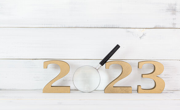 Upcoming 2023 New Year with Magnifying glass over white wood background, Search Goals Conccept.