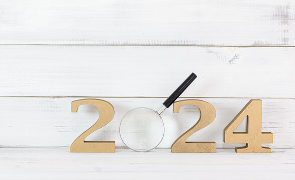 Upcoming 2024 New Year with Magnifying glass over white wood background, Search Goals Conccept.