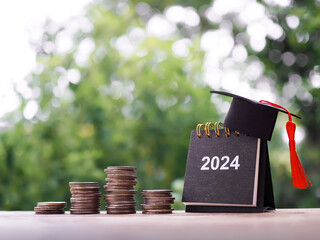 Study goals, 2024 Desk calendar with graduation hat and stack of coins. The concept of saving money...