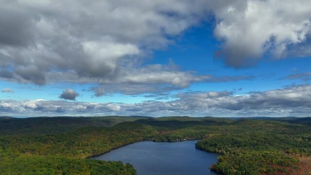 A high altitude view over Oscawana Lake in New York during the fall on a beautiful day. The camera dolly out slowly over the lake with the mountains in the background.