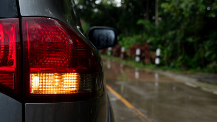 Close-up of turn light signal of gray car with water of rain on surface. Driving on wet cement road...