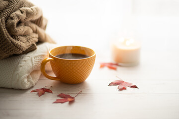 Fototapeta na wymiar Yellow cup of coffee with steam in autumn and knit warm sweater on the background. Cozy home