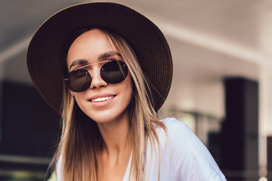 Stylish woman in sunglasses with open book looking at camera