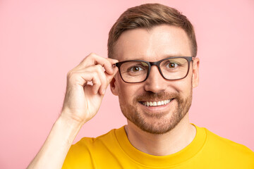 Positive relaxed confident bearded man with placid composed look touching and adjusting glasses....
