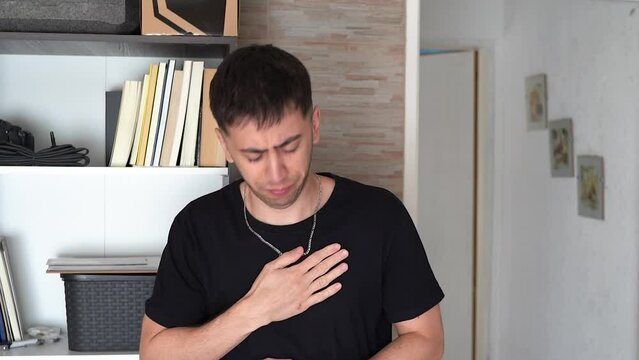 Young man at home feeling unwell and suffering from apparent chesty cough