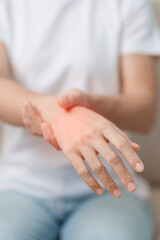 Woman having wrist pain during sitting on sofa at home, muscle ache due to De Quervain s...