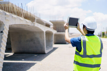 Professional senior Asian civil engineer working at the heavy infrastructure construction site, civil engineer - foreman inspecting the segmentation construction bridge.