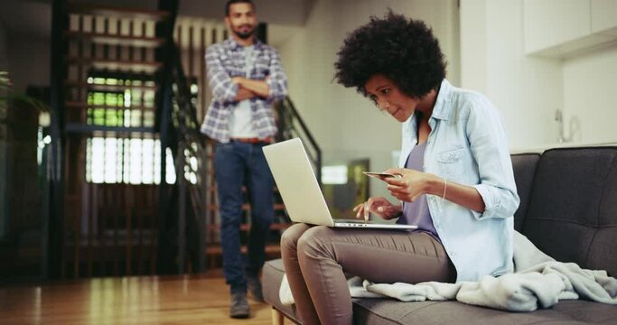 Woman, online shopping and laptop with credit card, ecommerce and internet purchase. Couple, shocked and hiding for spending money, boyfriend and man in home, digital product and financial payment