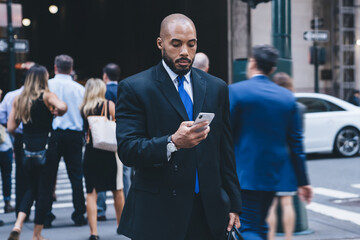 Black businessman walking with smartphone