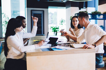 Enthusiastic multiracial colleagues discussing project and gesturing on meeting