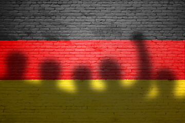 The refugees migrate to Germany . Silhouette of illegal immigrants . Europe union migration policy. Germany flag painted on a brick wall with protesters - obrazy, fototapety, plakaty