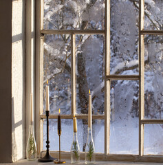 old window with winter landscape and burning candles on windowsill