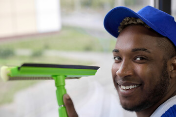 Close up of the happy face of a black man in a baseball cap working for a cleaning company. Cute...