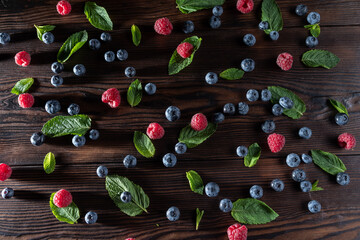 Berries and leaves are scattered on the table. Hard shadows of berries. Red and blue berries and...