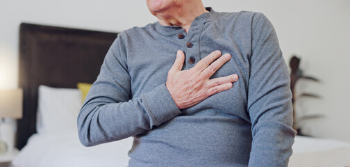 Hands, chest pain and closeup of senior man in bedroom with injury, hurt or accident at nursing...