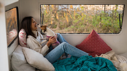 Caucasian woman sitting in a van hugging with dog Jack Russell Terrier. Travel in a camper in the...