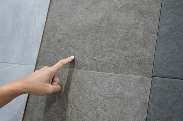 Male hand pointing at stone tile texture choosing sample material for floor finishing in home design store. Home improvement concept - 666365343