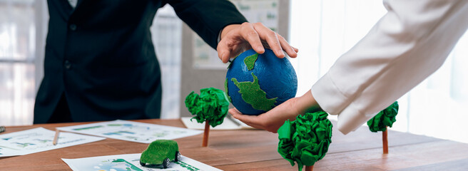 Business people holding paper earth together over office table. Green corporate company...